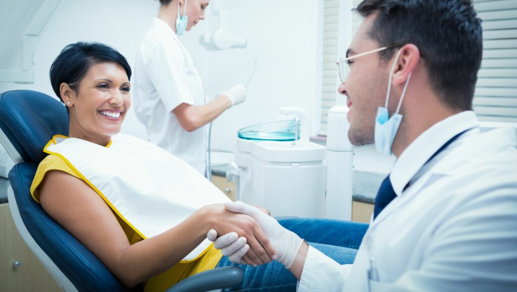 dentista sorridente che stringe la mano al suo paziente